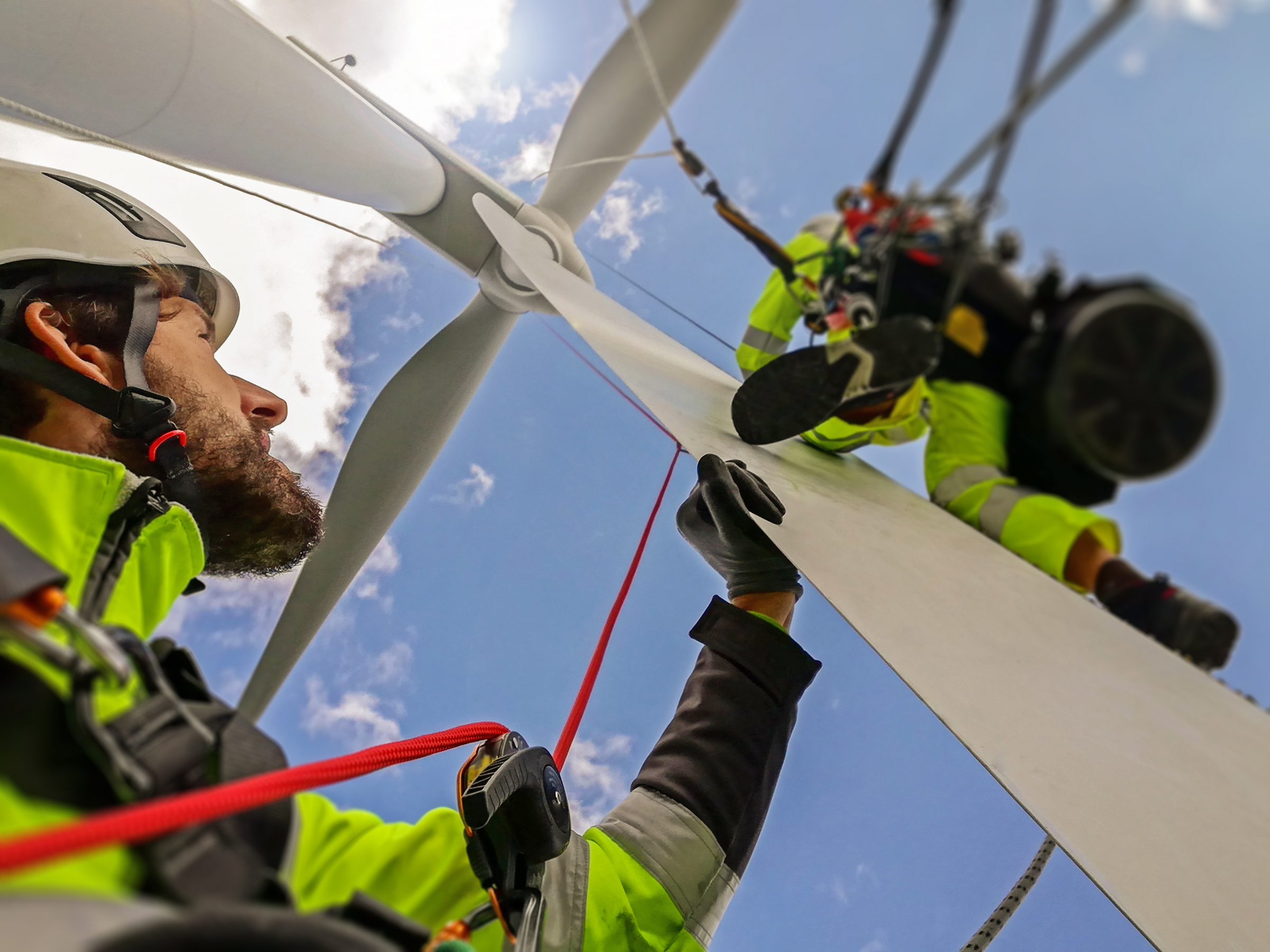 Wind turbine maintenance at height against blue sky