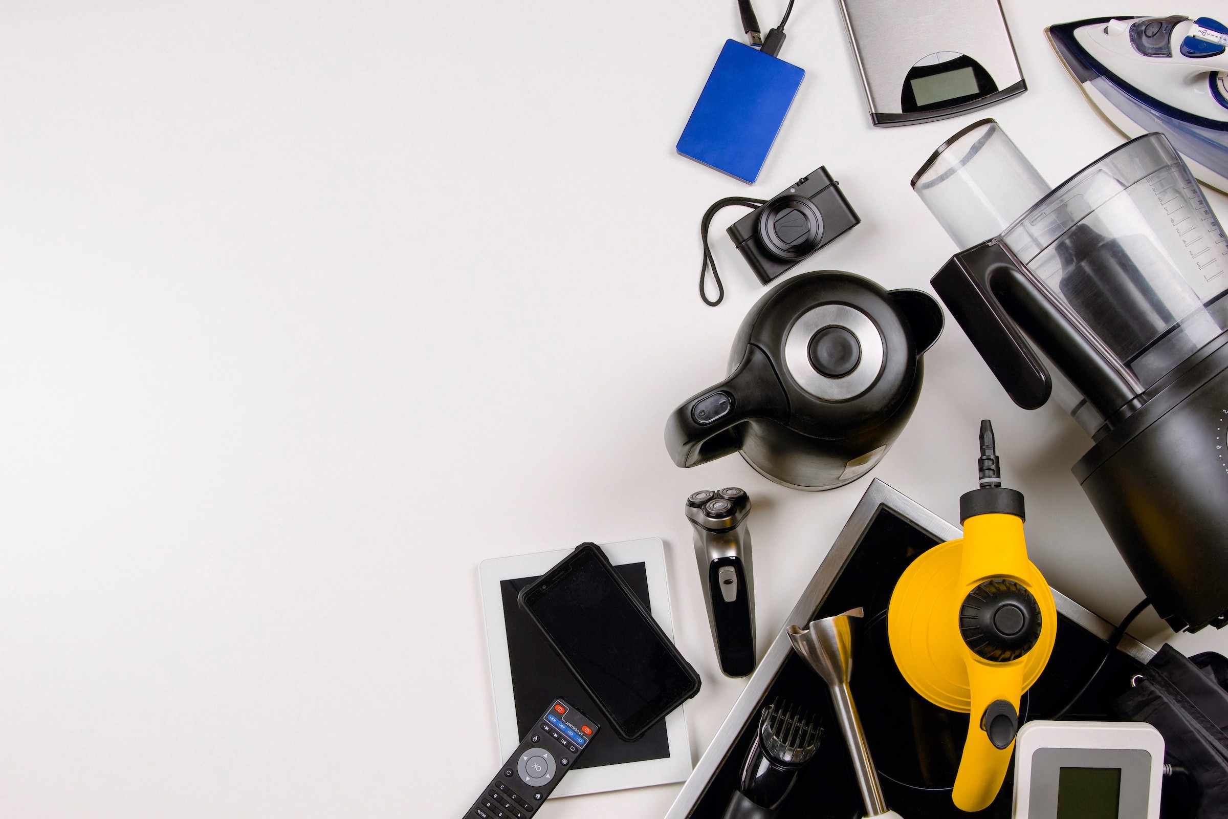 Assortment of small electrical appliances and electronic devices arranged for recycling on a white background.