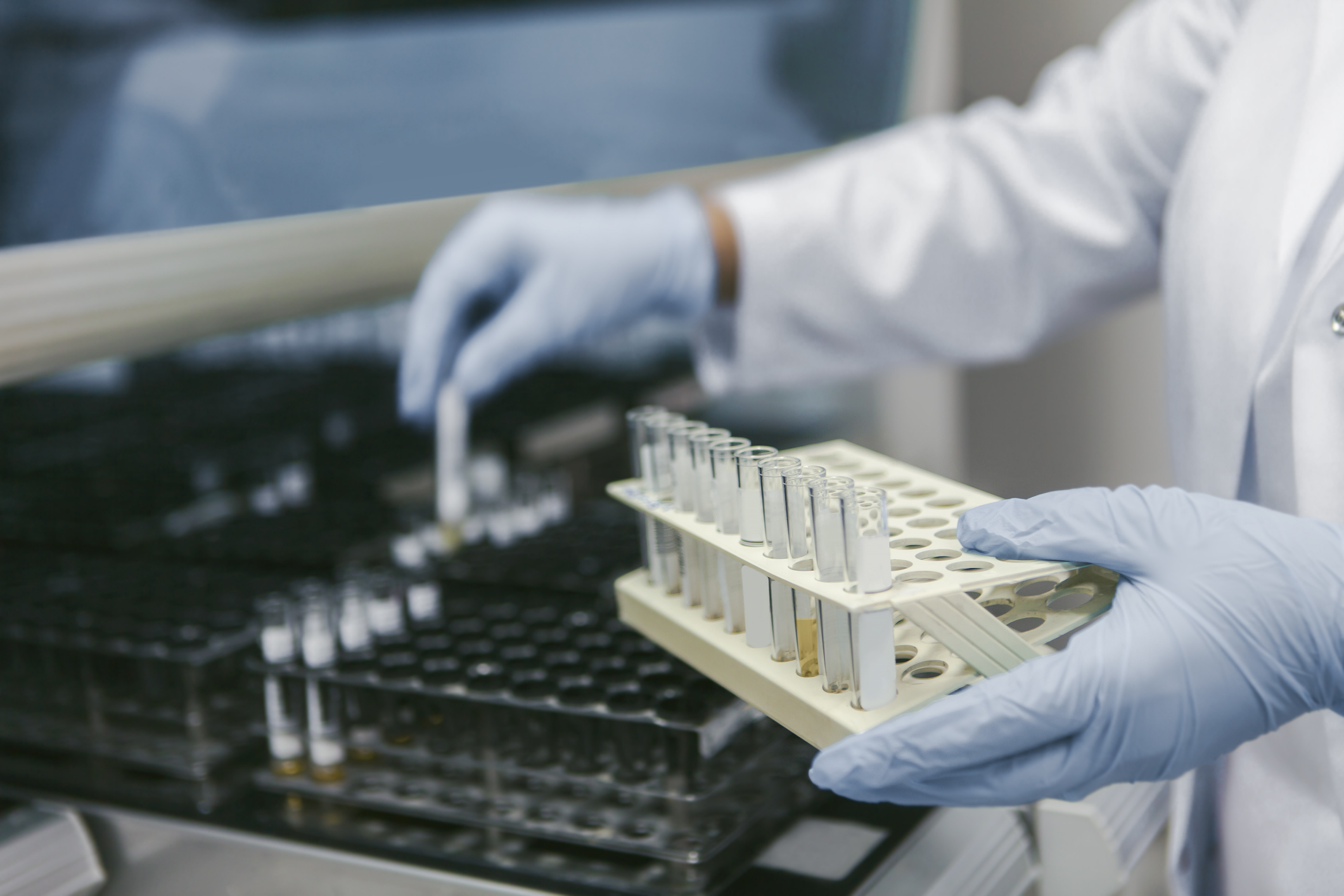 Laboratory technician handling test tubes in a laboratory.